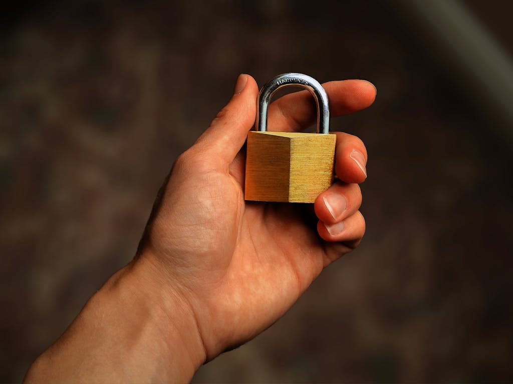 Hand holding a brass padlock, symbolizing security and protection